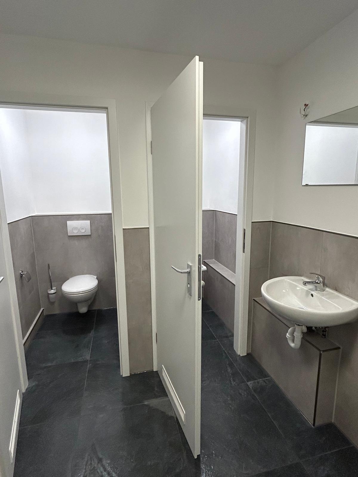 Fertiggestellter WC-Bereich mit dunklem Boden und grauen Wandflächen