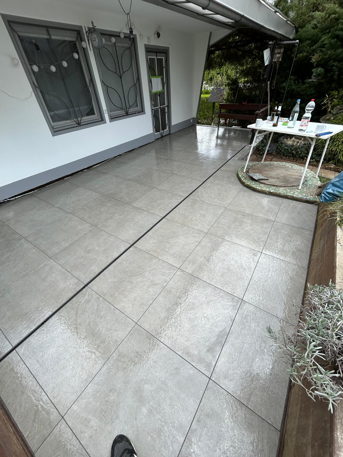 Fertig verlegte graue Terrassenplatten auf einem überdachten Außenbereich