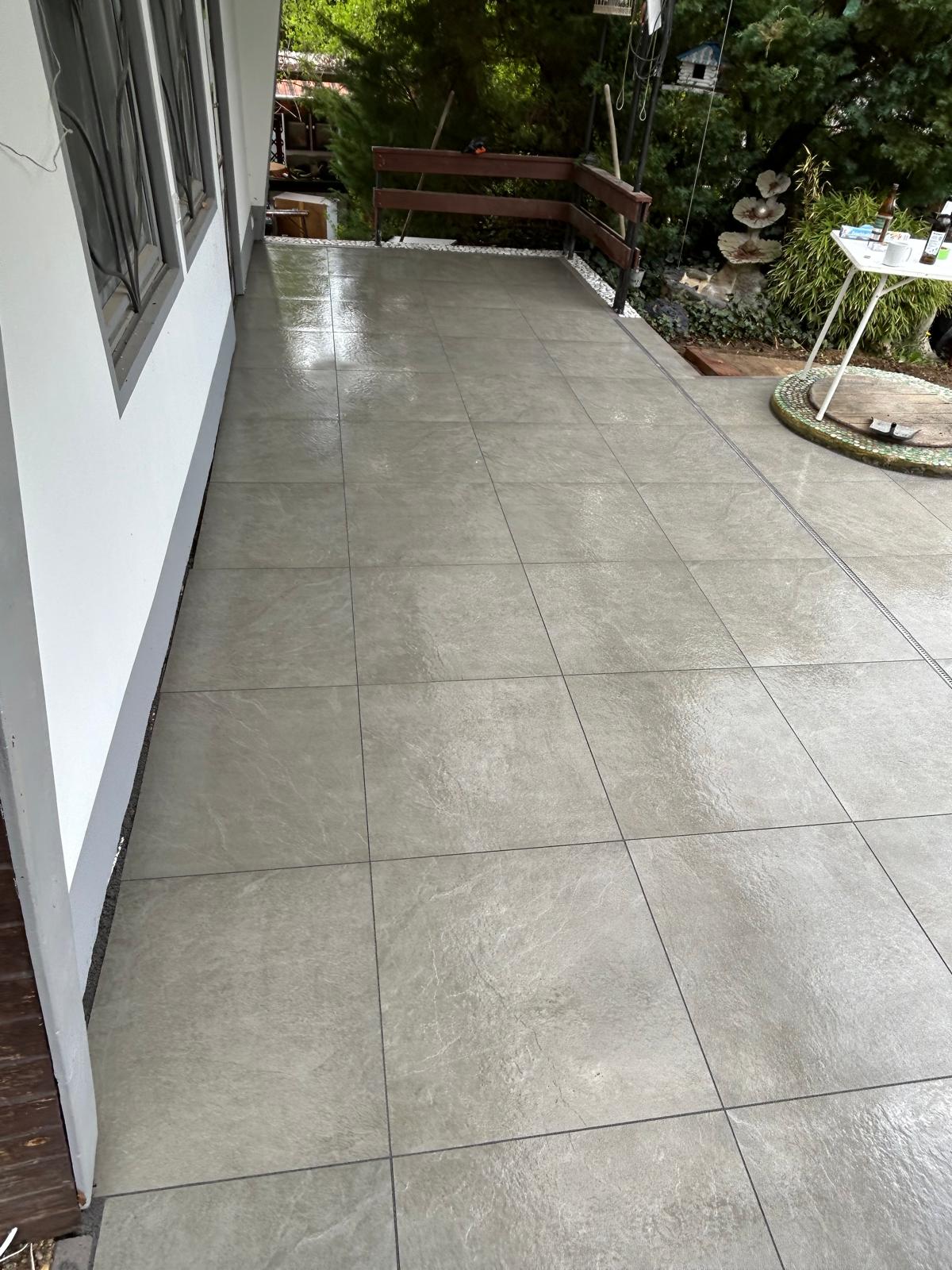 Fertiggestellte graue Terrassenfläche mit sauberen Anschlüssen an Haus und Geländer