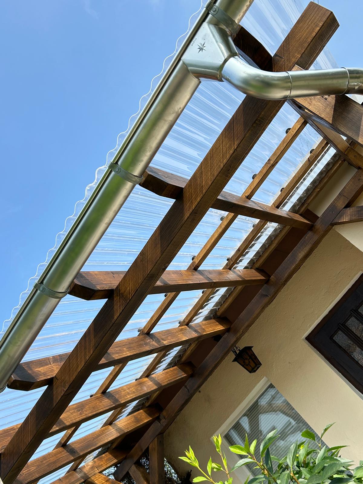 Detailansicht einer Holz-Terrassenüberdachung mit transparenter Eindeckung und Dachrinne