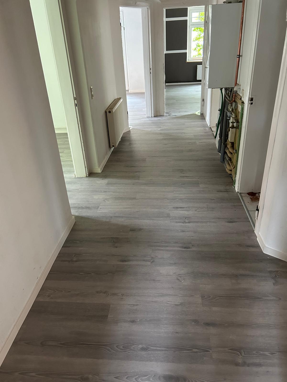 Grauer Vinylboden mit einheitlichem Verlauf durch Flur und angrenzende Räume