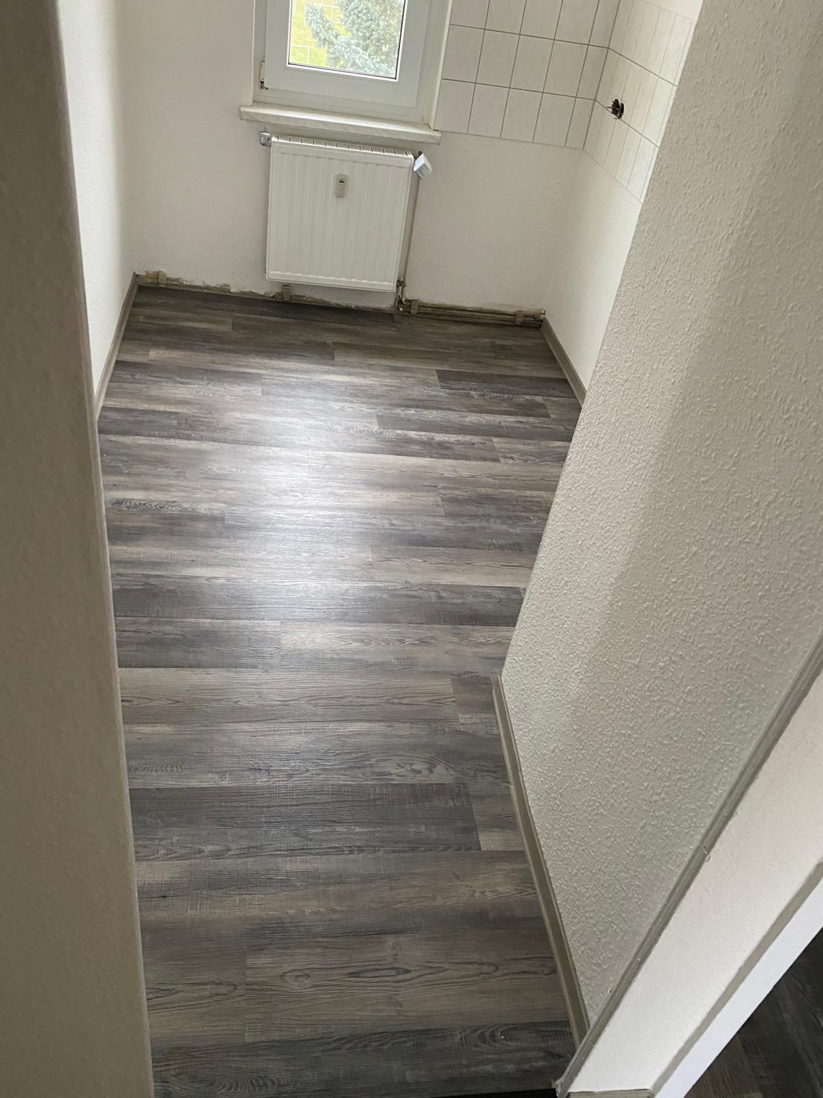 Schmaler Nebenraum mit sauber verlegtem Vinylboden in grauer Holzoptik