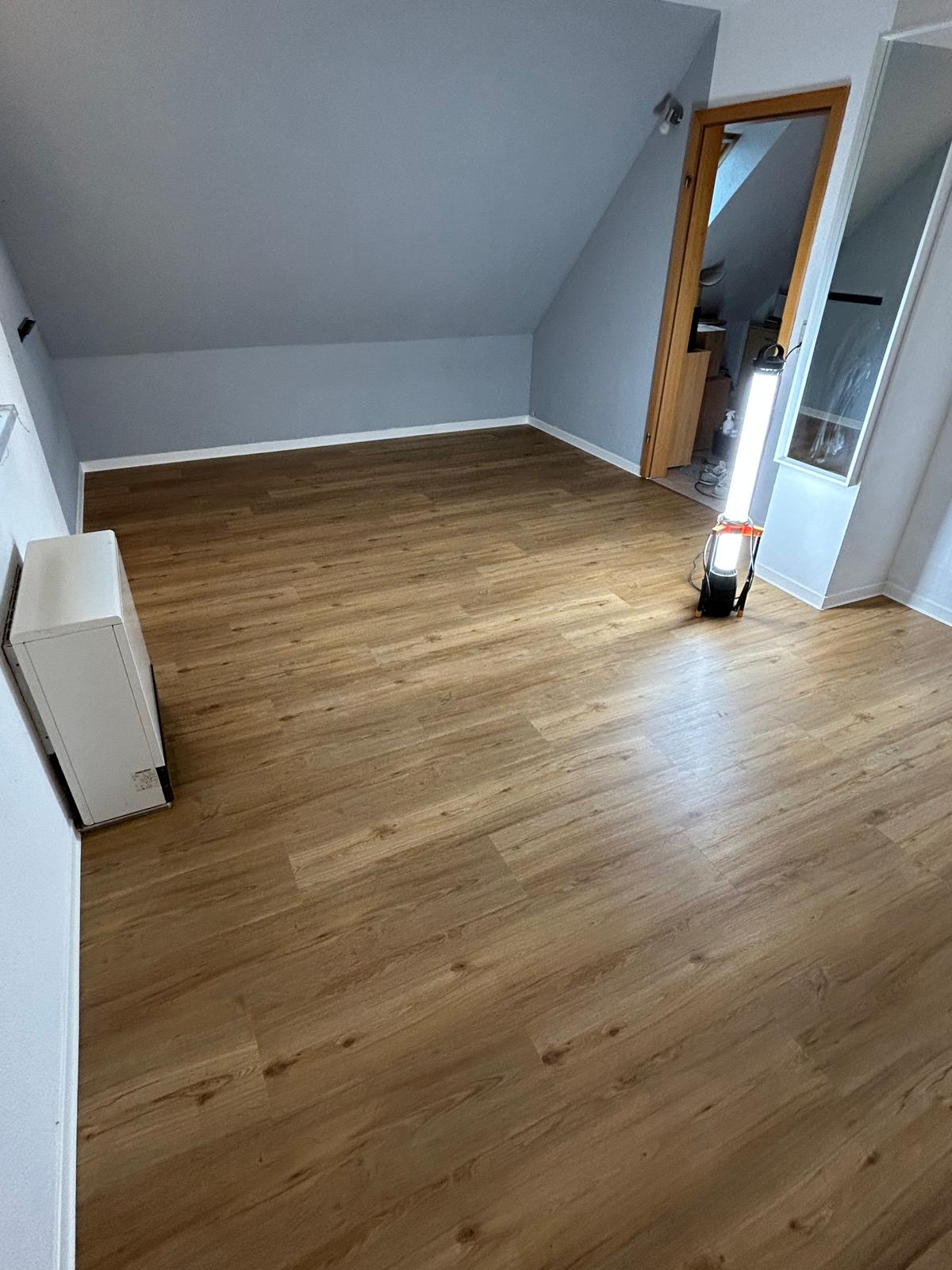 Dachgeschosszimmer mit sauber verlegtem warmem Vinylboden unter einer Dachschräge